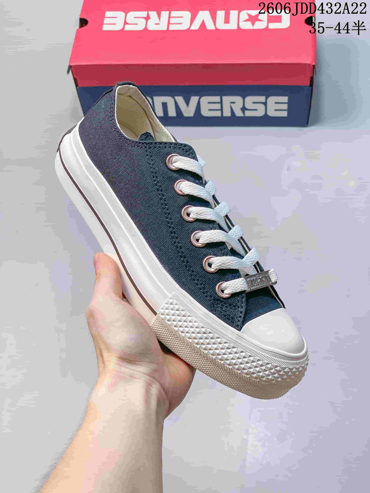 Close view of a navy low-top sneaker with white laces and a textured rubber toe bumper