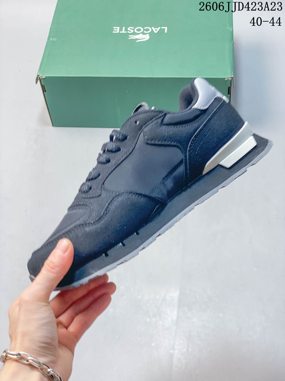 Side view of a navy Lacoste sneaker with layered panels and a contrasting heel detail.