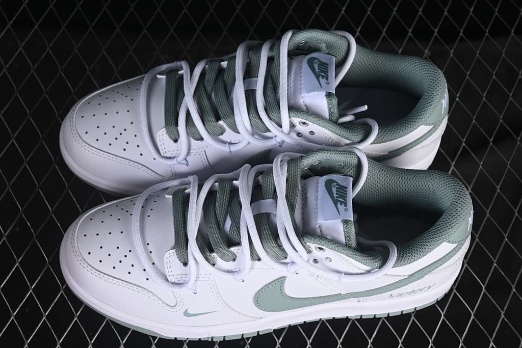 Overhead view of a pair of white and sage-green low-top sneakers with contrasting laces.