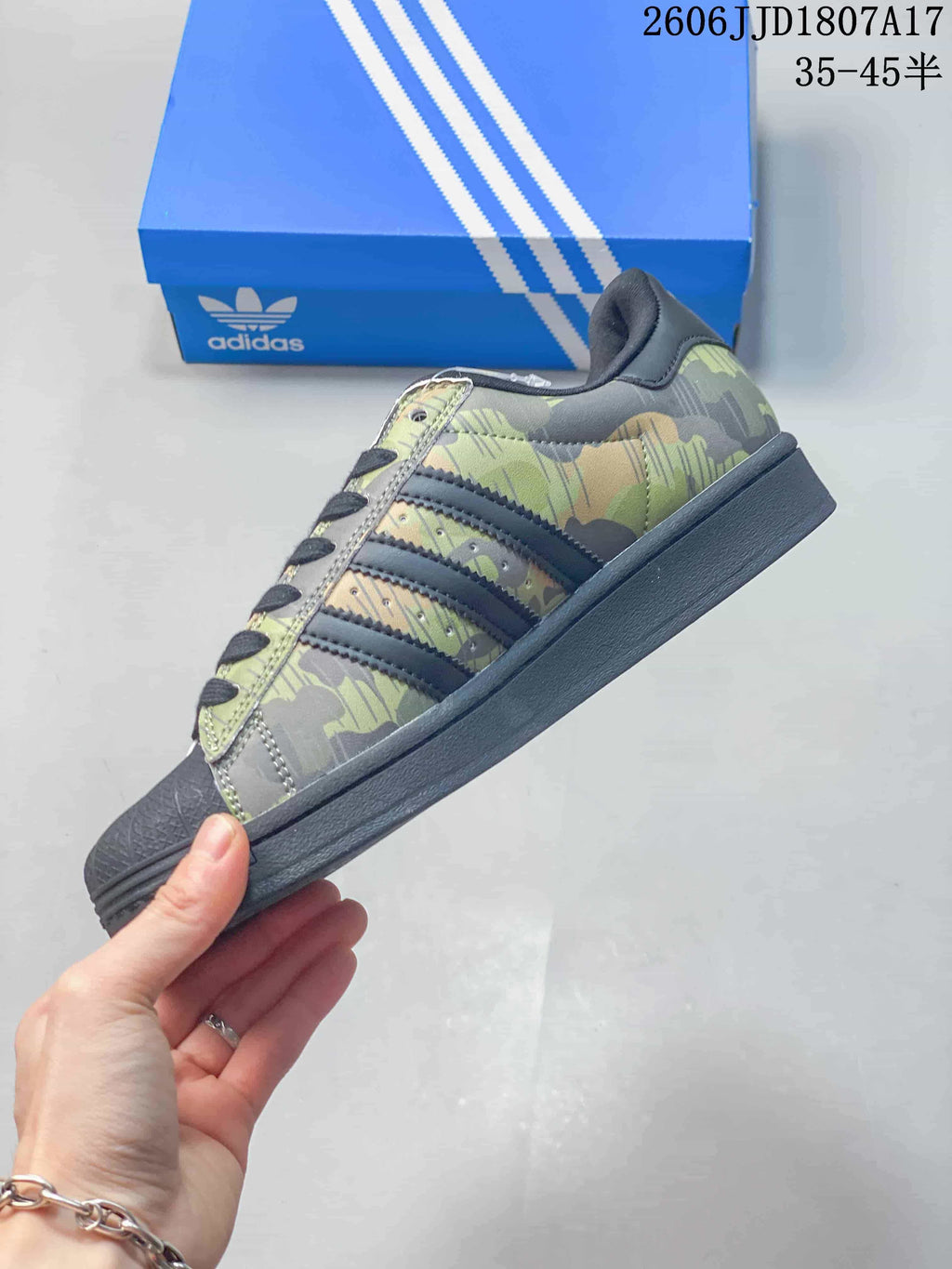 Side profile of the camouflage Superstar sneaker with dark stripes and sole