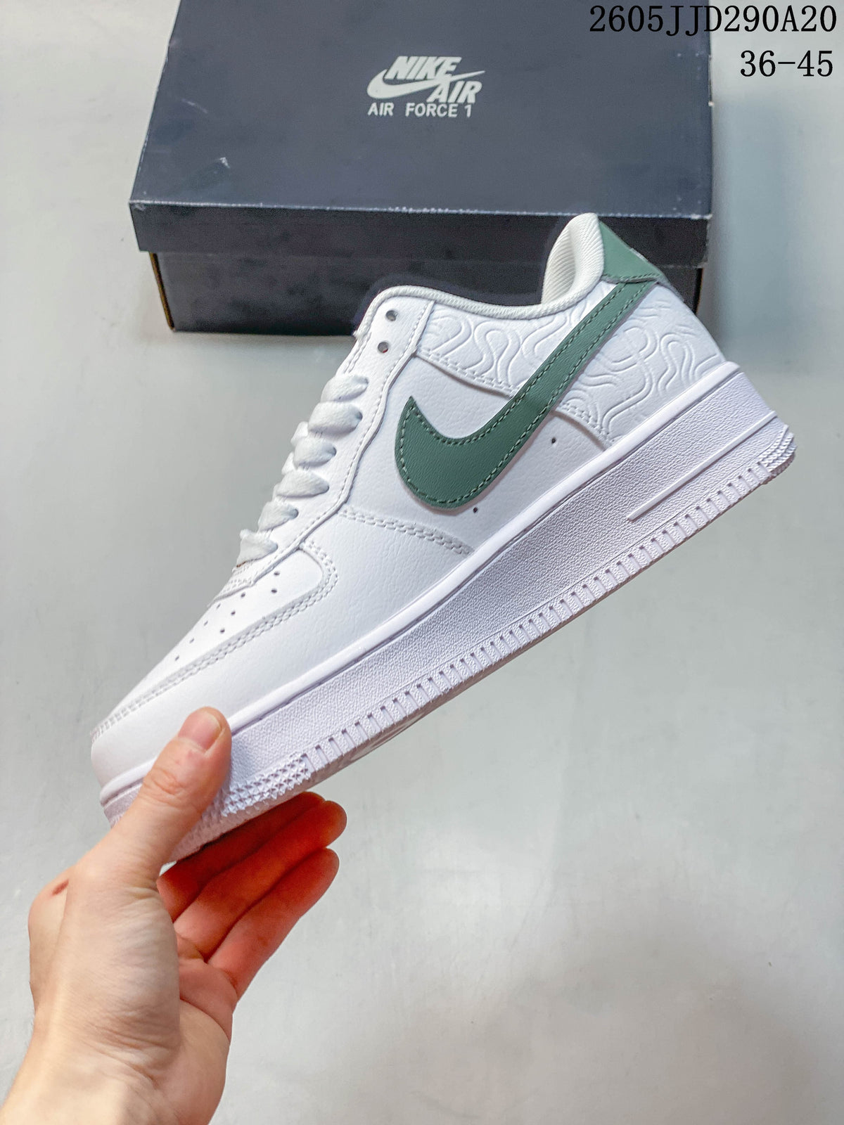 Side view of a white Nike Air Force 1 Shadow sneaker with green swoosh and embossed heel detailing.