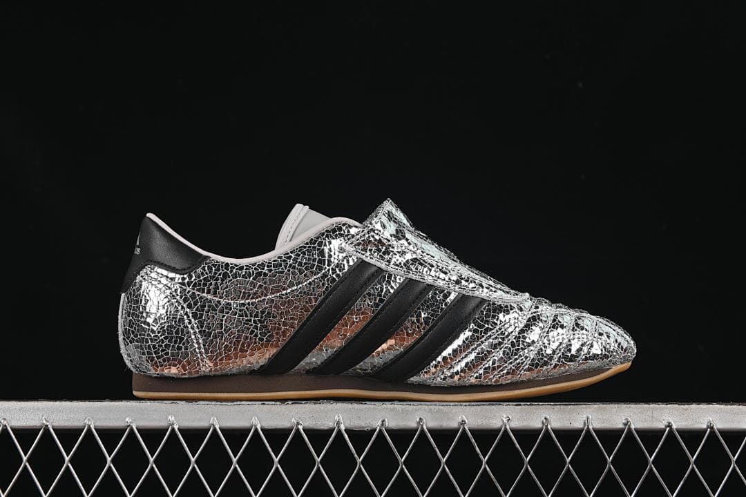 Side profile showing the silver metallic upper, black stripes and low-profile sole.