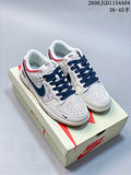 Pair of light-colored Nike SB Dunk Low sneakers with navy laces, navy Swooshes, red heel accents, and a shoe box.