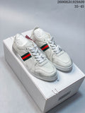Pair of white low-top sneakers with red-and-green side stripes, shown on a box.
