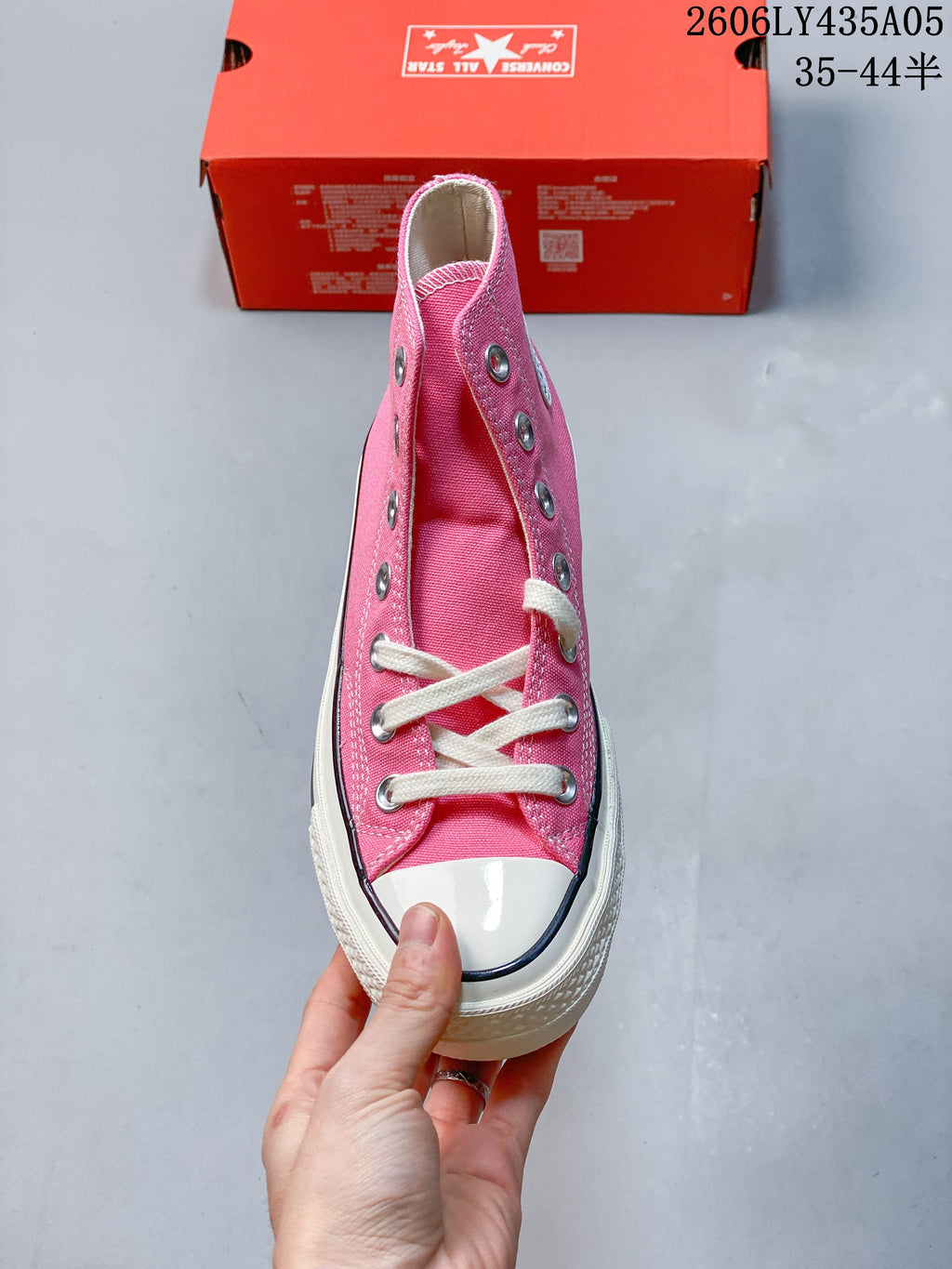 Front view of a pink high-top sneaker with white laces and a rubber toe cap