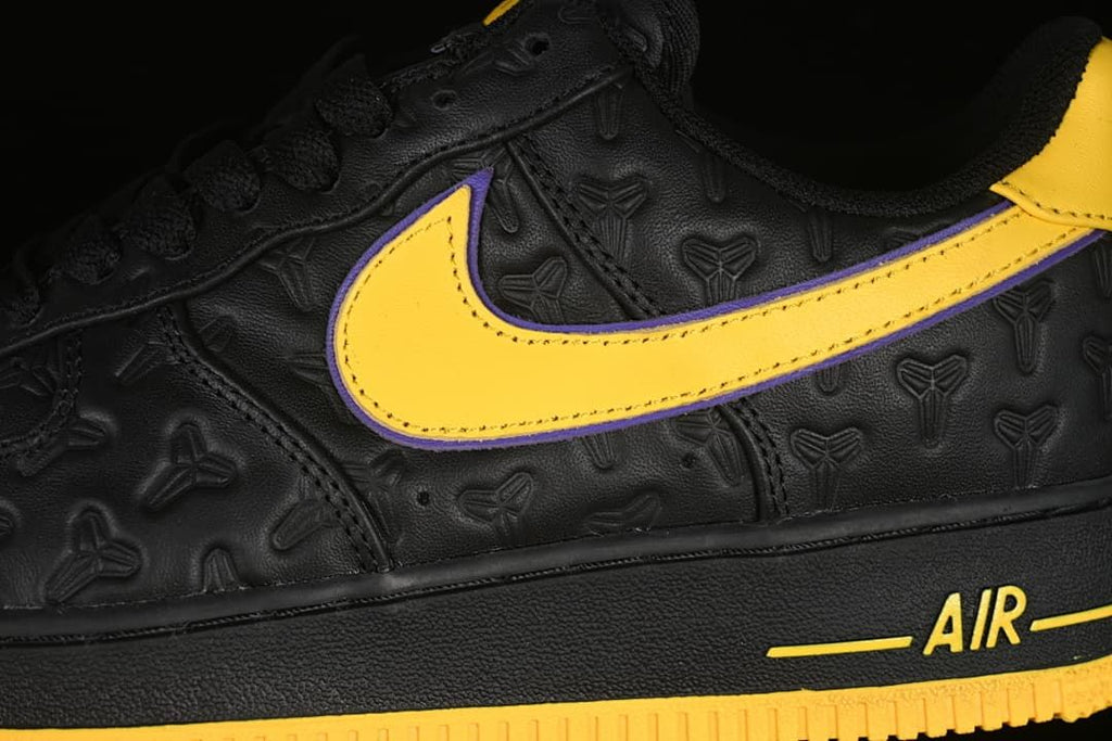 Close-up of the yellow Swoosh with purple edging and embossed upper pattern.