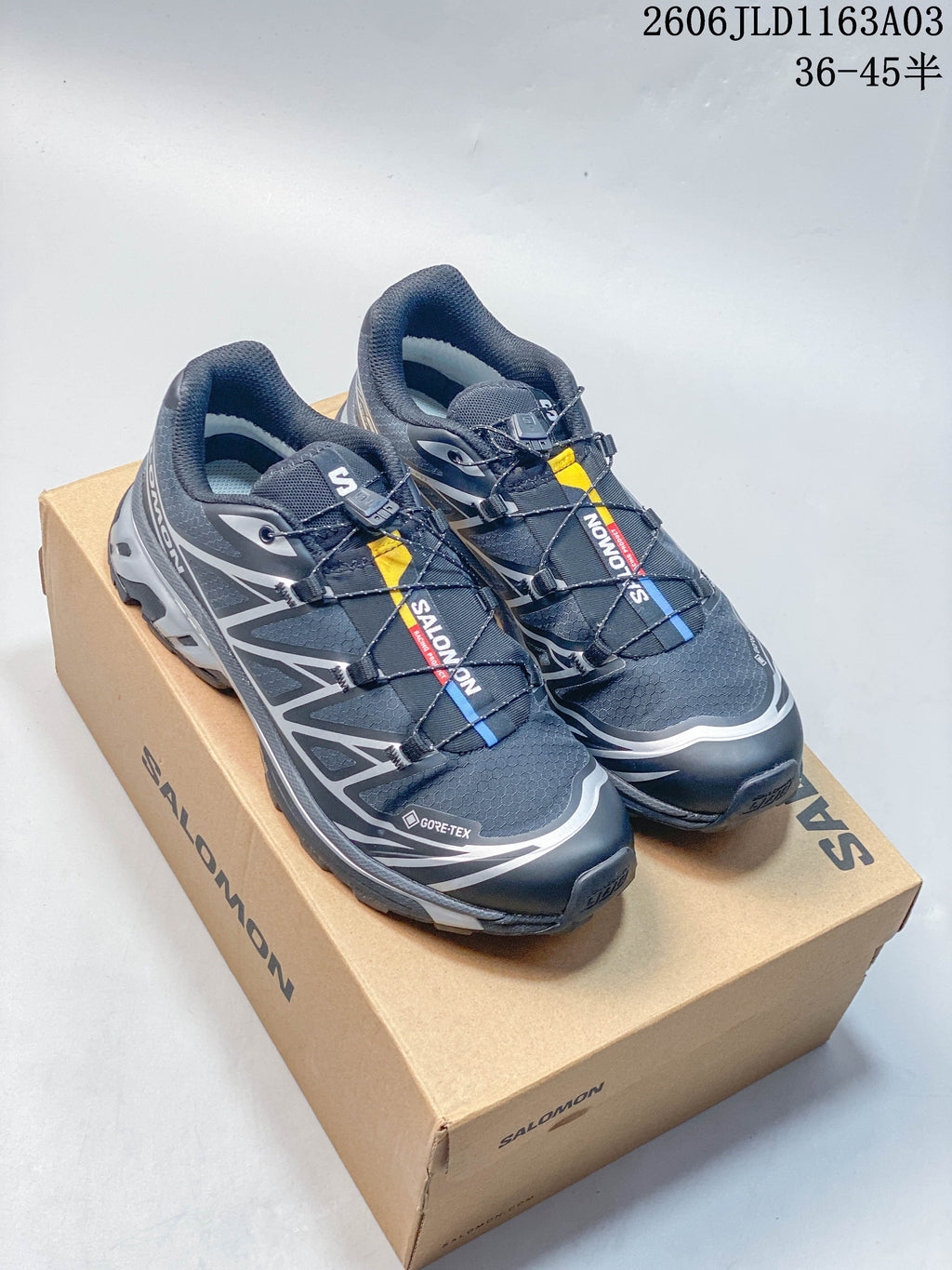 Pair of dark gray and black Salomon XT-6 GTX sneakers with silver accents, shown on a shoe box