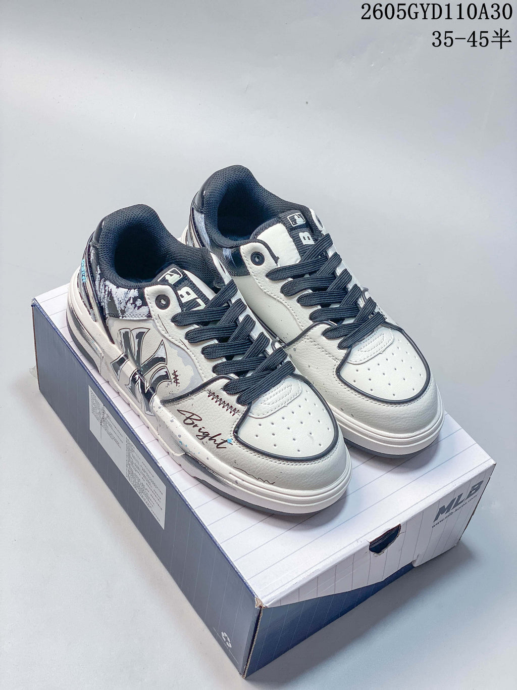 Pair of white and navy MLB low-top sneakers with graphic side detailing, shown on a box