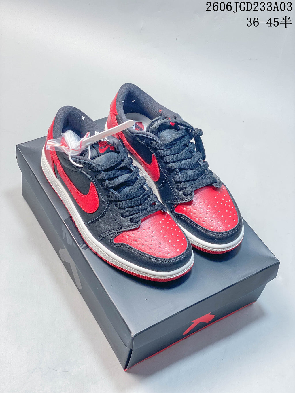 Pair of black and red low-top sneakers on a shoebox, shown from above