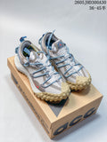 Light gray and blue Nike ACG low-top shoes with patterned uppers and rugged tan outsoles, shown on a shoebox.