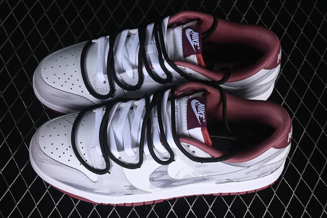Pair of white low-top sneakers with gray details, burgundy lining, and black cord-style straps
