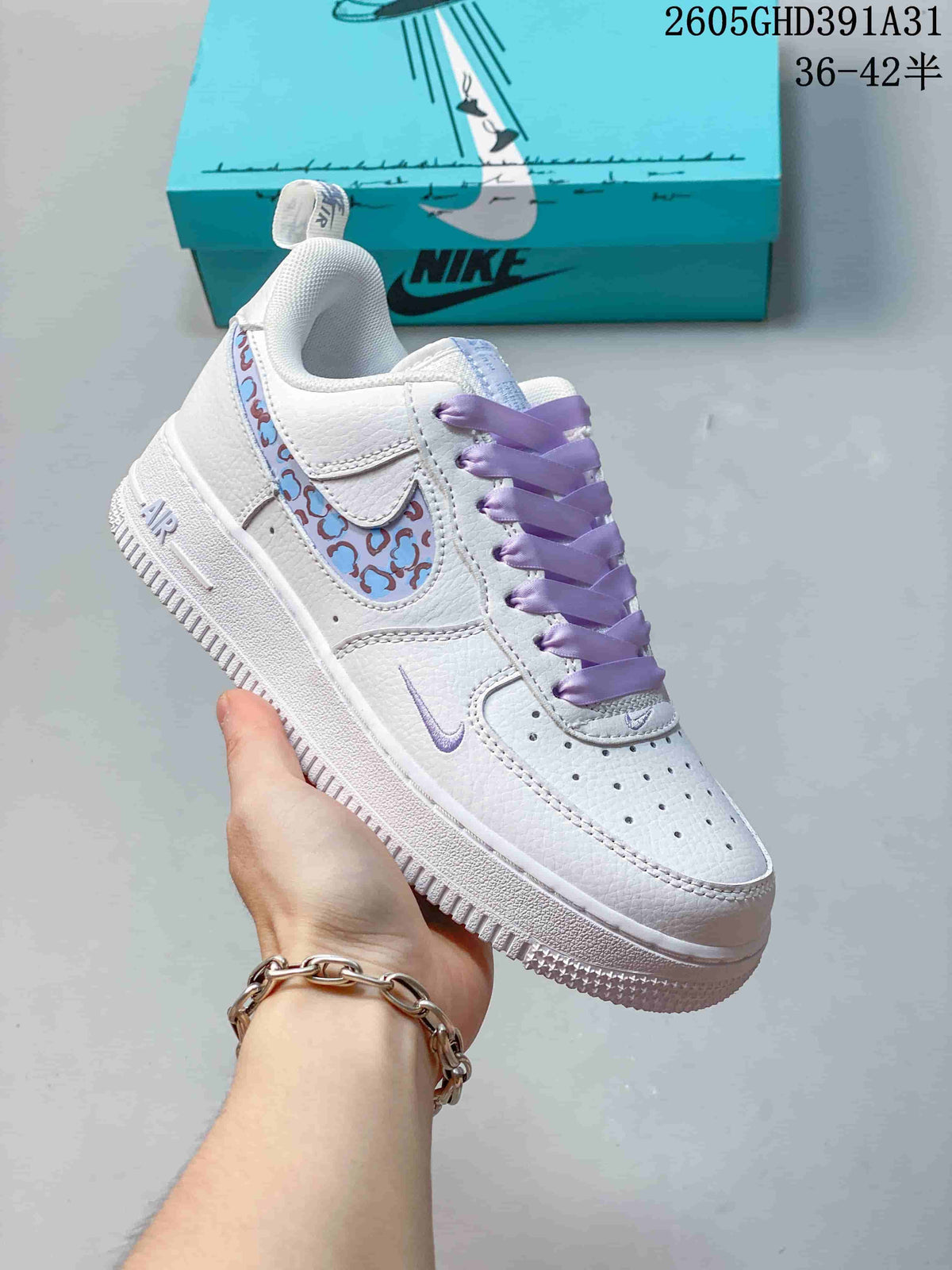 Angled side view of a white Nike Air Force 1 Low sneaker with lavender laces and a colorful patterned side panel