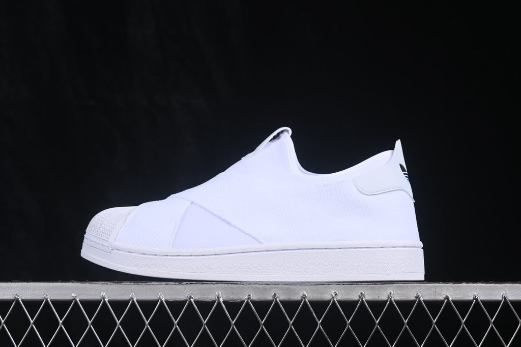 Side profile of a white adidas slip-on sneaker with a shell-style toe and layered upper.