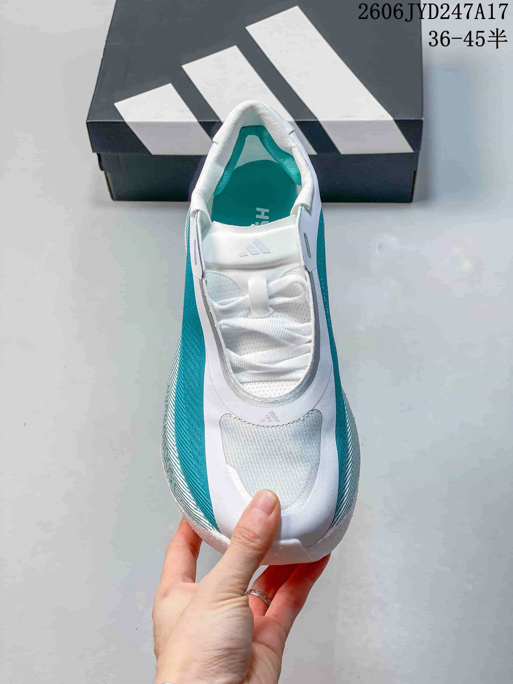 Top view of a white and teal sneaker with laces and a mesh-like toe panel