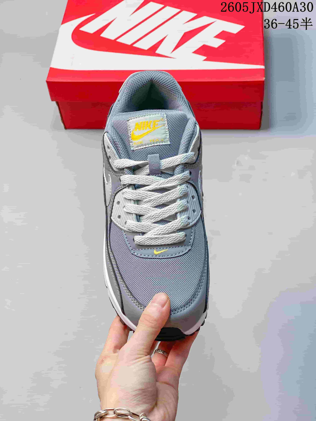 Top view of the grey Nike Air Max 90 sneaker showing its laces, mesh panels and yellow details.