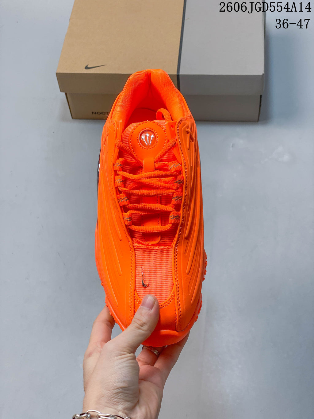Top view of the orange lace-up sneaker with a round tongue emblem