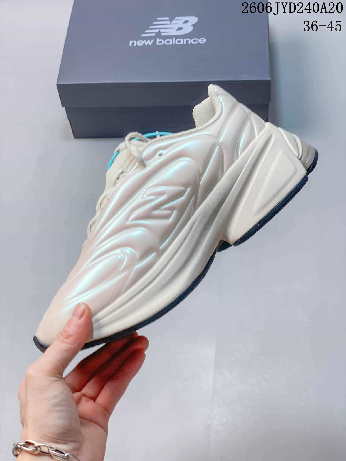 Side profile of a pearl-white New Balance sneaker with sculpted panels and a chunky sole.
