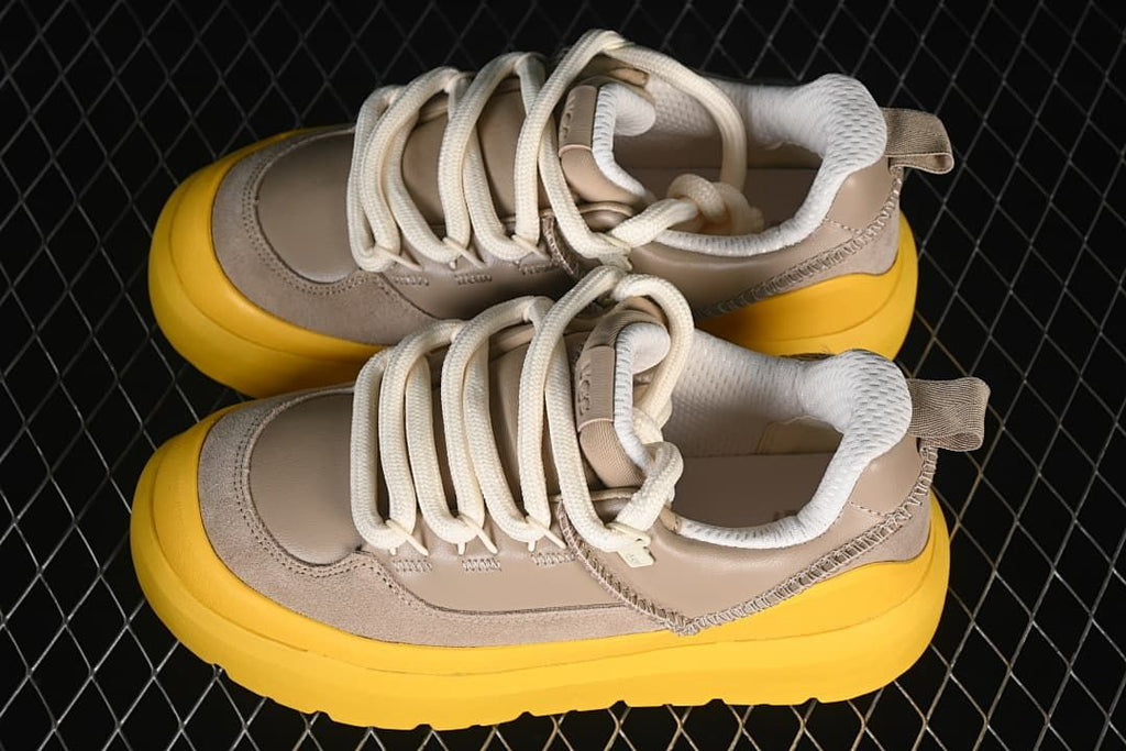 Pair of taupe sneakers with cream laces and yellow soles