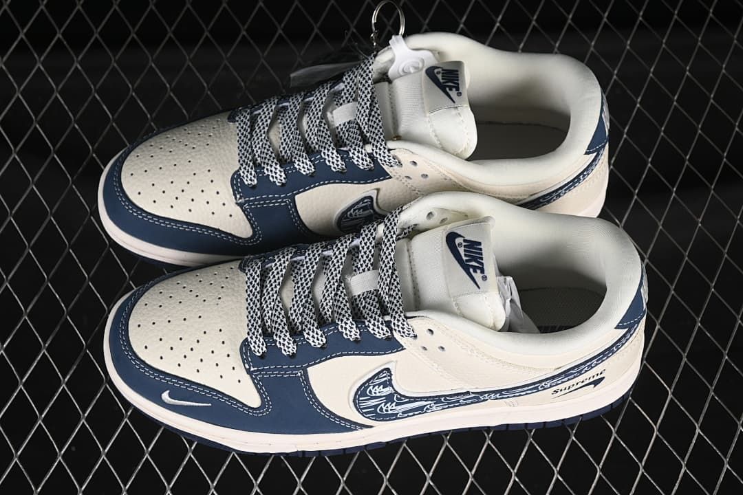 Top view of a pair of cream and navy low-top sneakers with patterned laces and perforated toe panels.