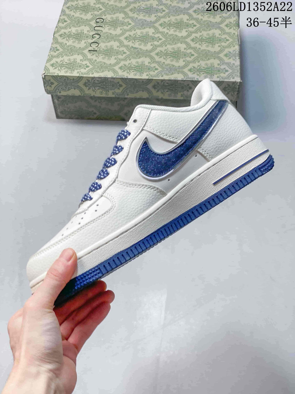 Side view of a white low-top sneaker with blue Swoosh and outsole accents; image text shows style code 2606LD1352A22 and size range 36–45.5.