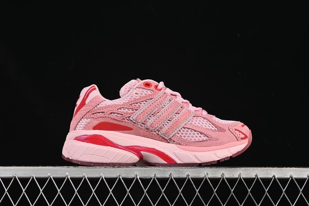 Side profile of a pink sneaker with layered stripes and red midsole accents.