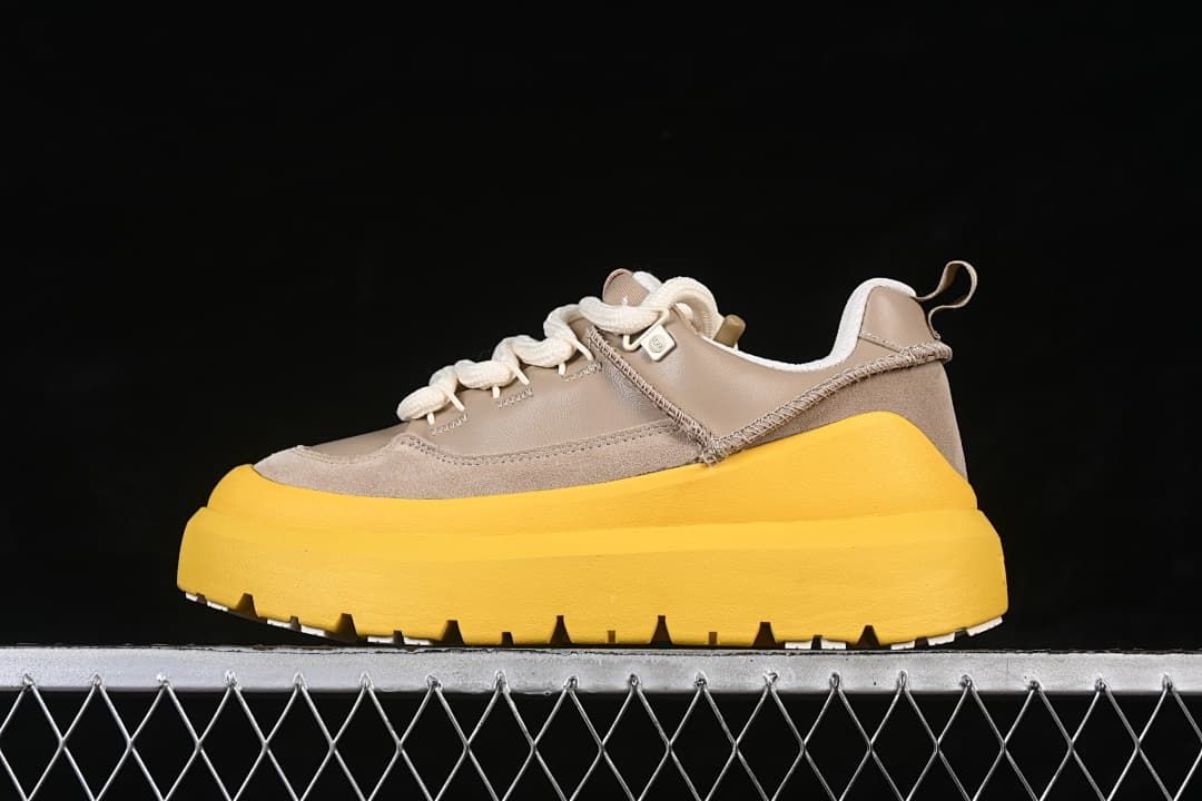Side view of a taupe UGG lace-up sneaker with cream laces and a bright yellow sole
