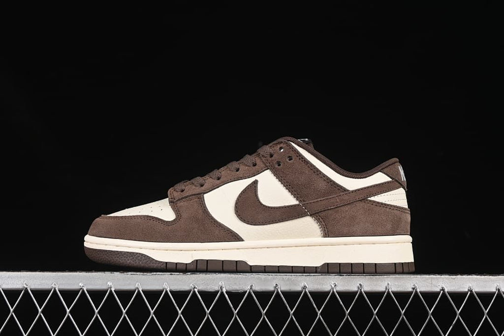 Side view of brown and off-white Nike SB Dunk Low sneakers against a black background