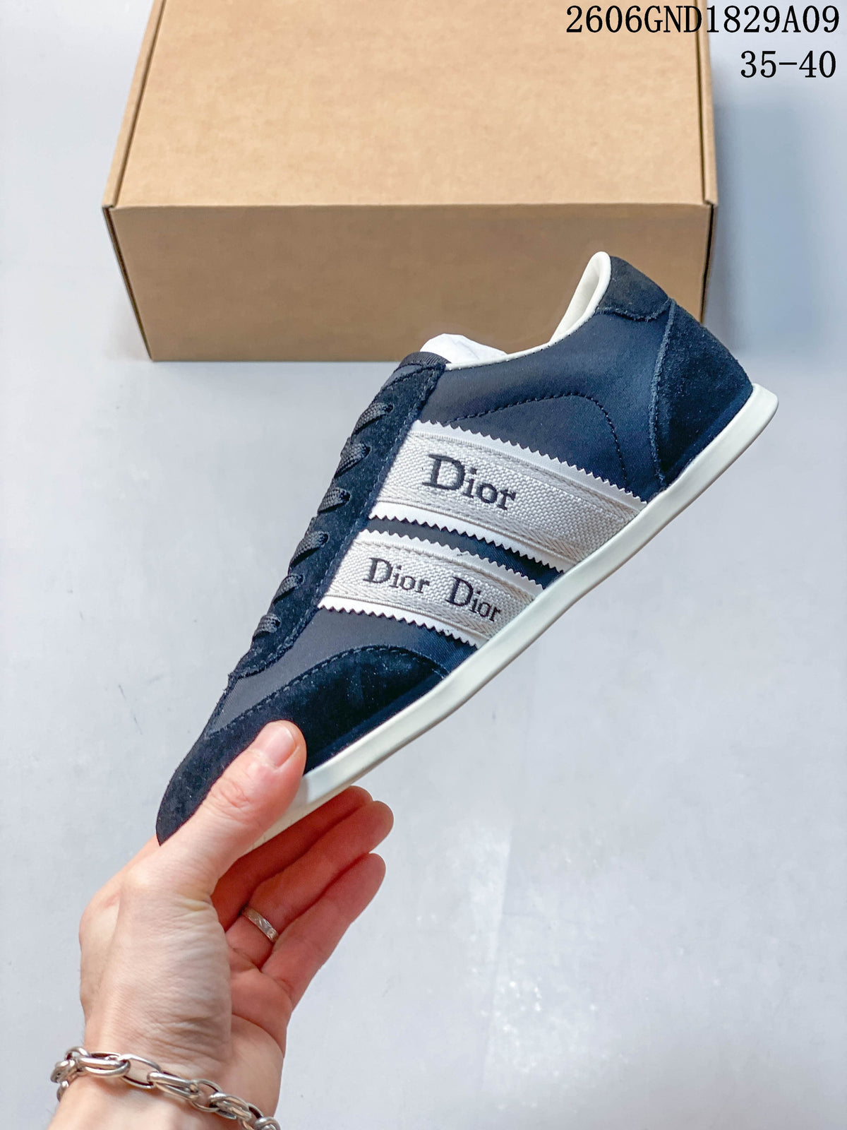 Side view of a navy low-top sneaker showing white ribbon-style side panels and a light-colored sole.