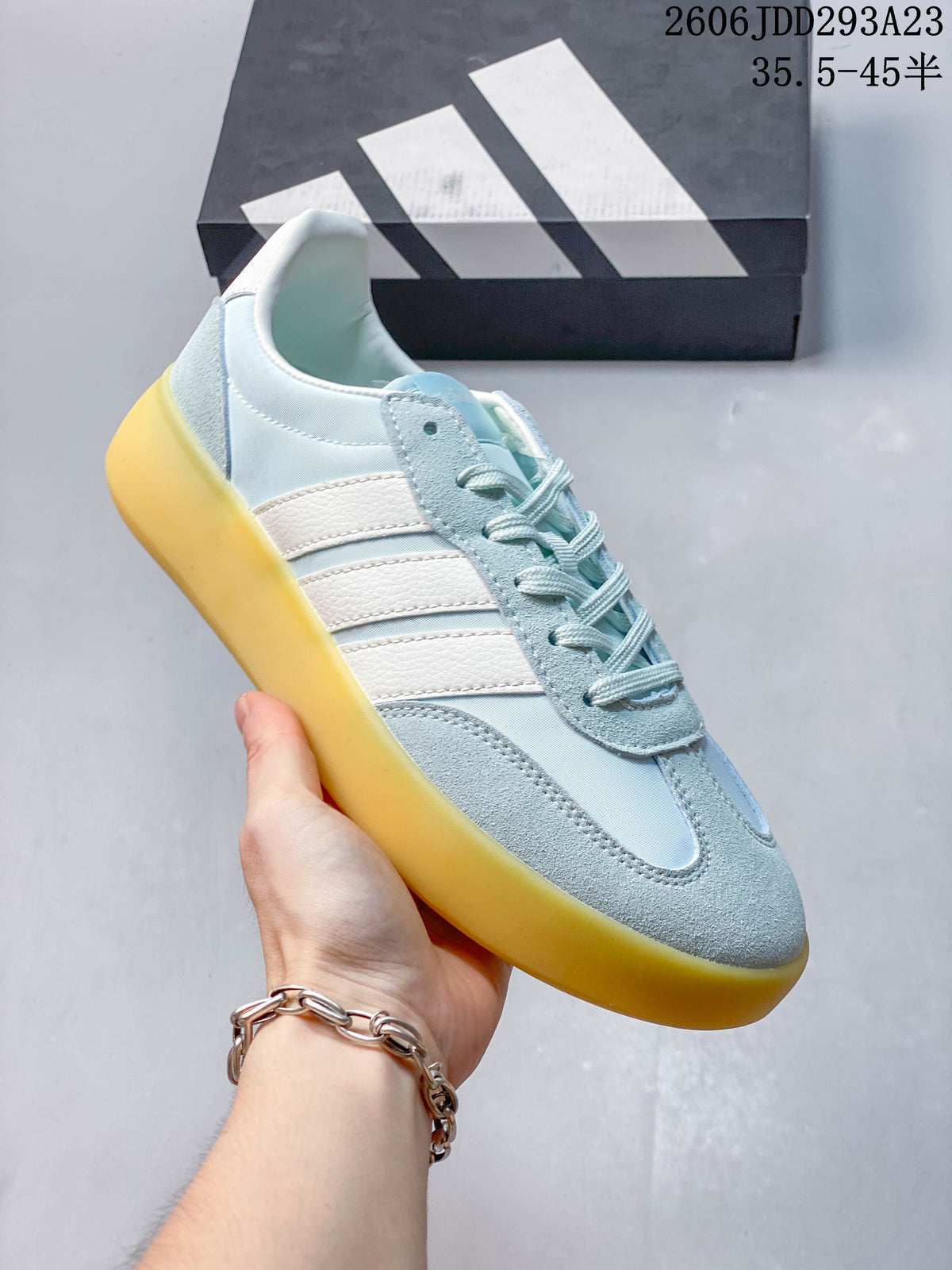 Close-up of a pale blue Adidas Barreda Decode sneaker with white side stripes and a contrasting yellow-toned sole.