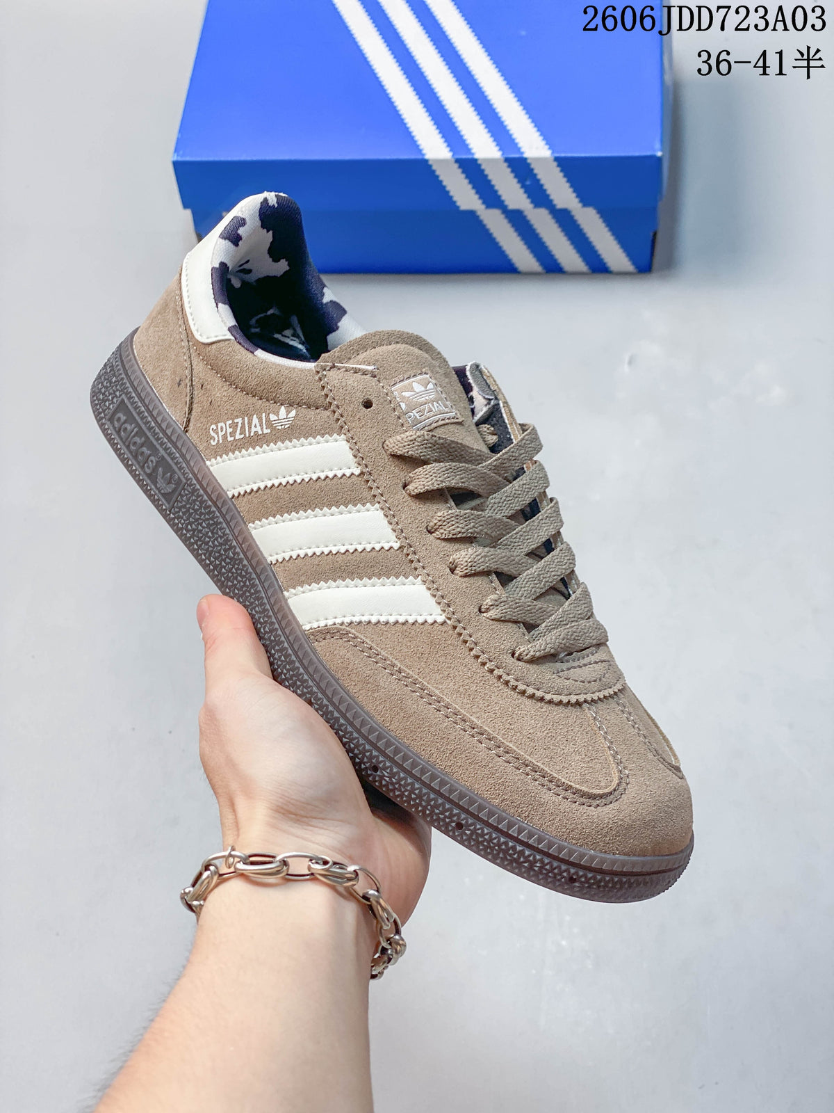 Side view of a taupe Adidas Handball Spezial sneaker with pale stripes and a dark outsole.