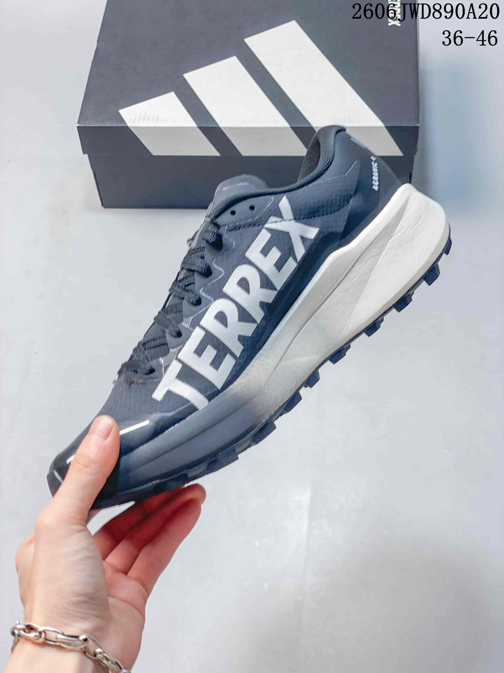Side view of the gray Terrex shoe with large lettering, three-stripe detail and a light-colored midsole.