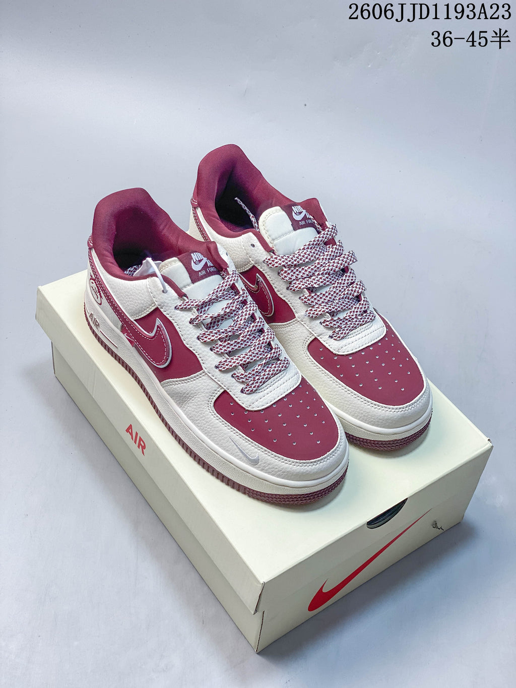 Pair of white and burgundy Nike Air Force 1-style sneakers on a shoebox.