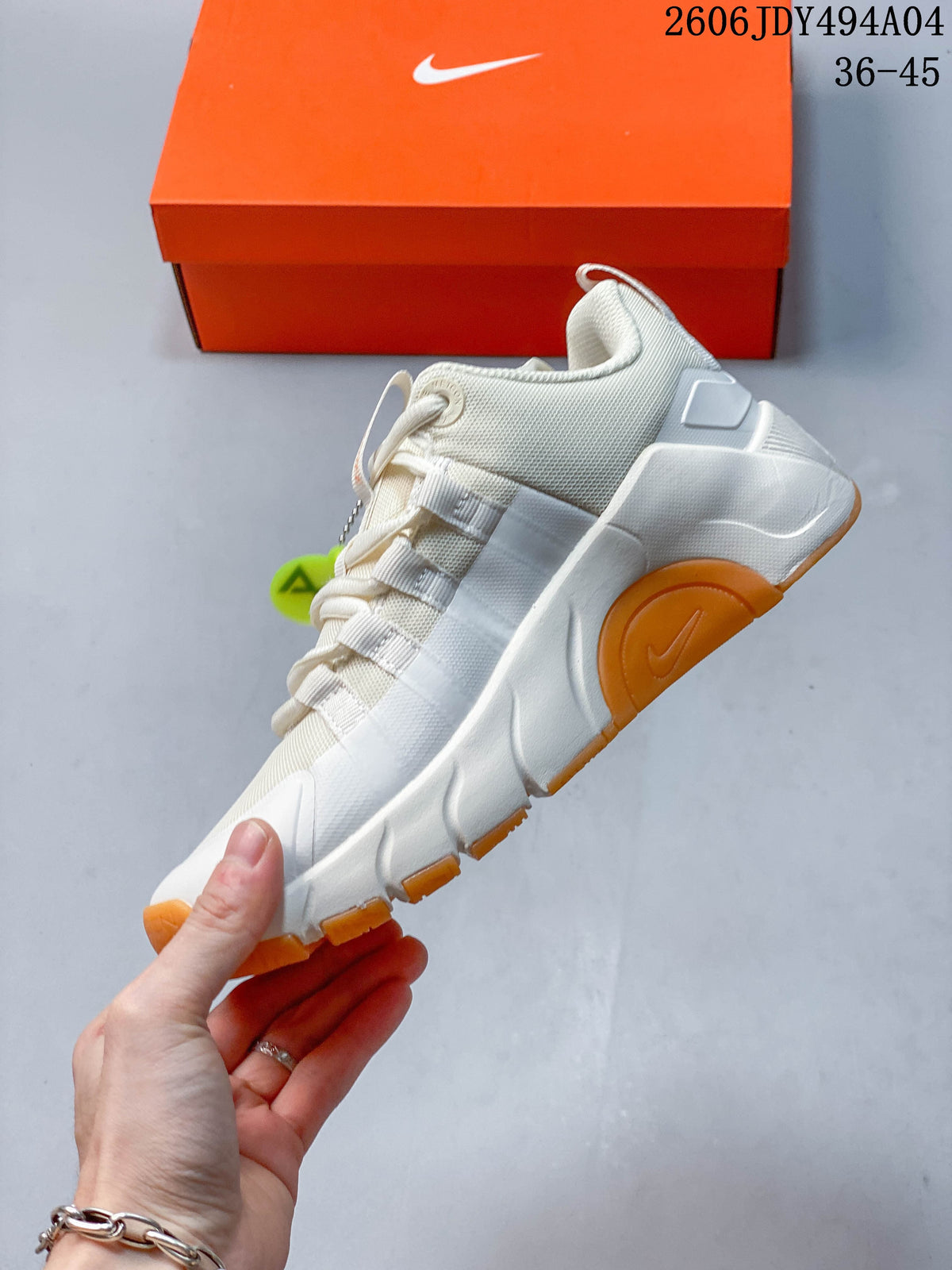 Side profile of the light-colored training shoe with orange outsole sections.