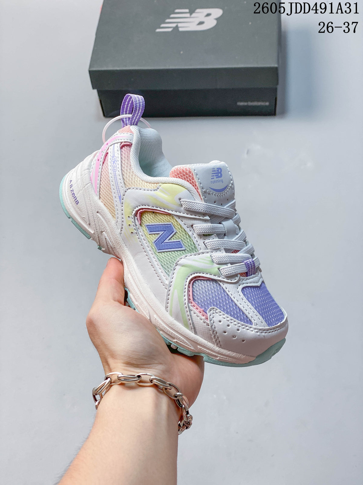 Multicolor kids' New Balance 530 lace-up sneaker with pastel accents, shown in hand.