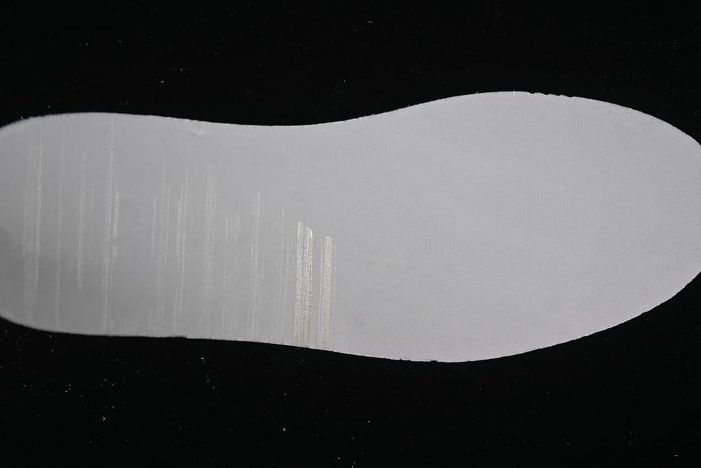 Plain white shoe-shaped piece photographed on a black background