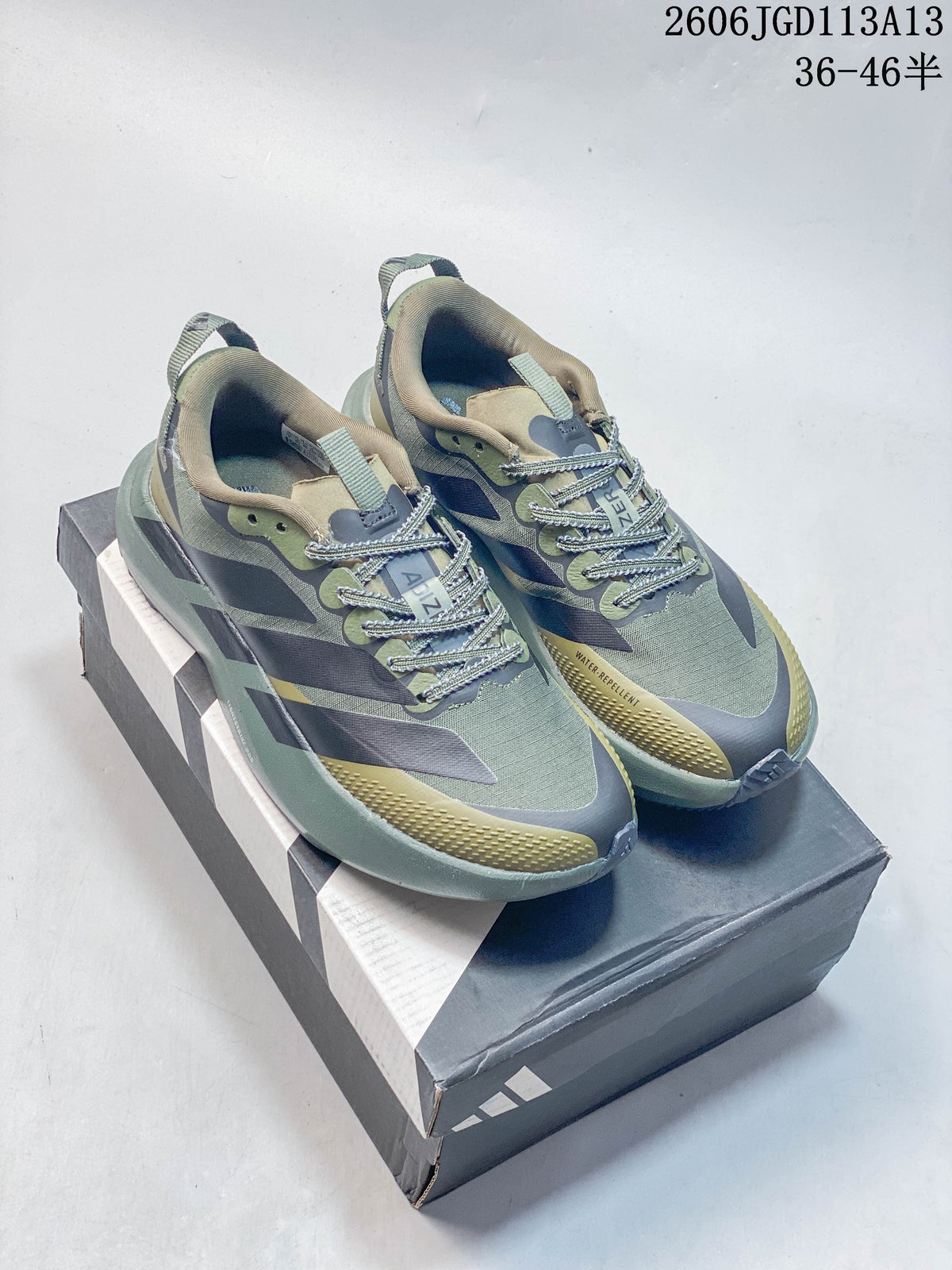 Pair of olive, gray, and muted yellow Adidas Adizero Evo SL ATR running shoes on a shoe box