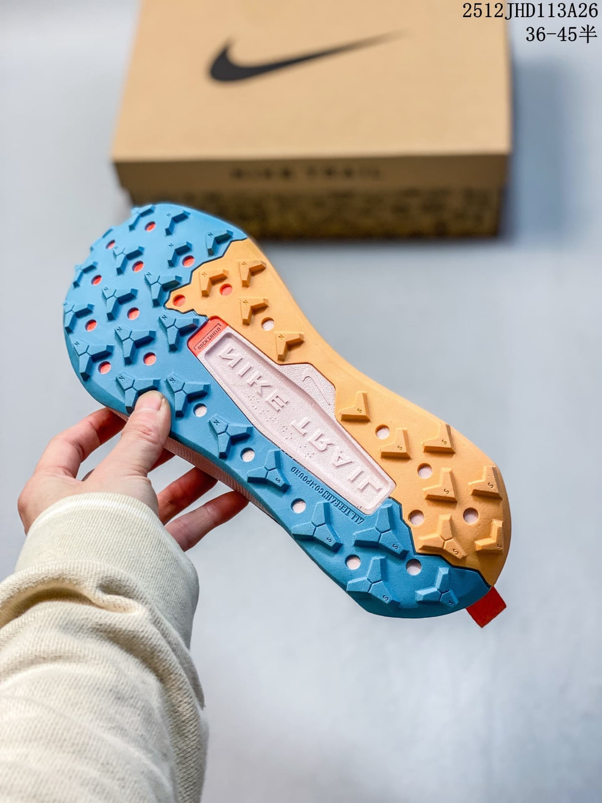 Close-up of the blue and orange lugged outsole of a Nike ReactX Wildhorse 10 shoe.
