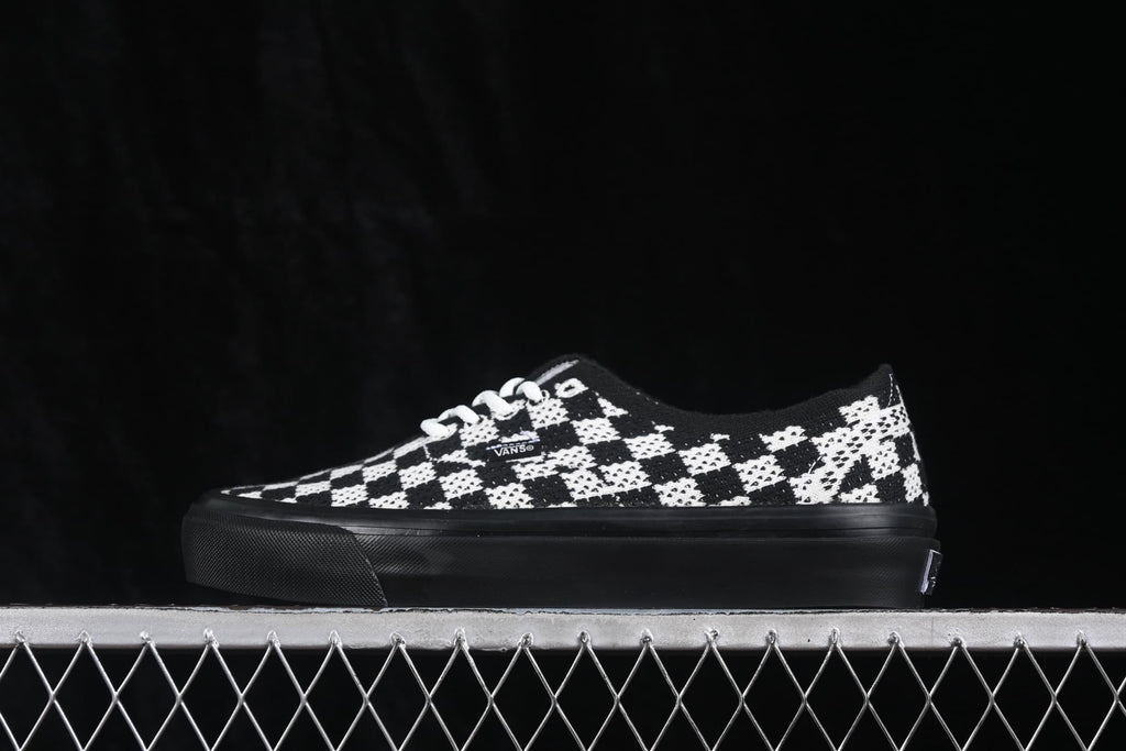 Side profile of one sneaker showing the low-top shape, checkerboard upper and black rubber sole.