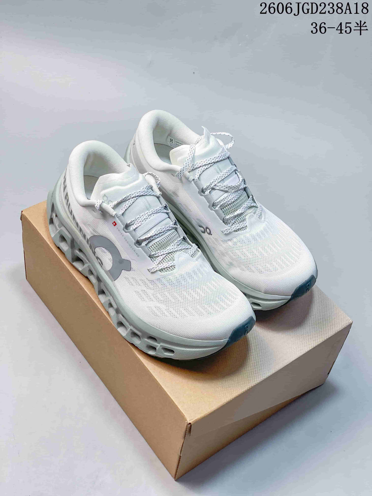 Pair of white On Cloudmonster sneakers with gray details, shown on a box