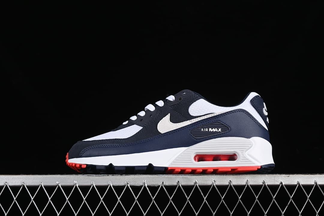 Side view of the navy, white, and red Nike Air Max 90 sneaker