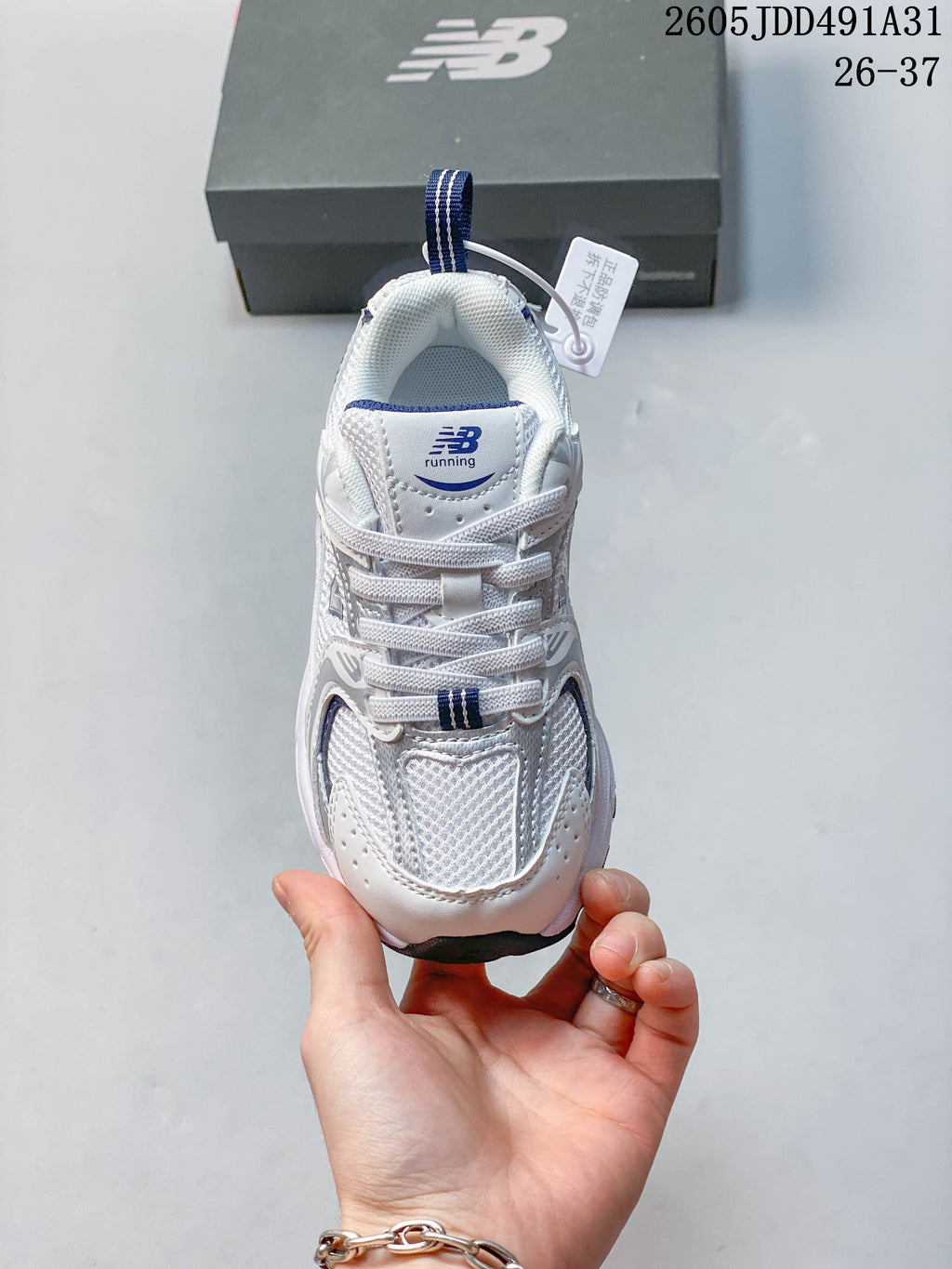Top view of a white and navy New Balance kids' sneaker with laces and a mesh-look upper.