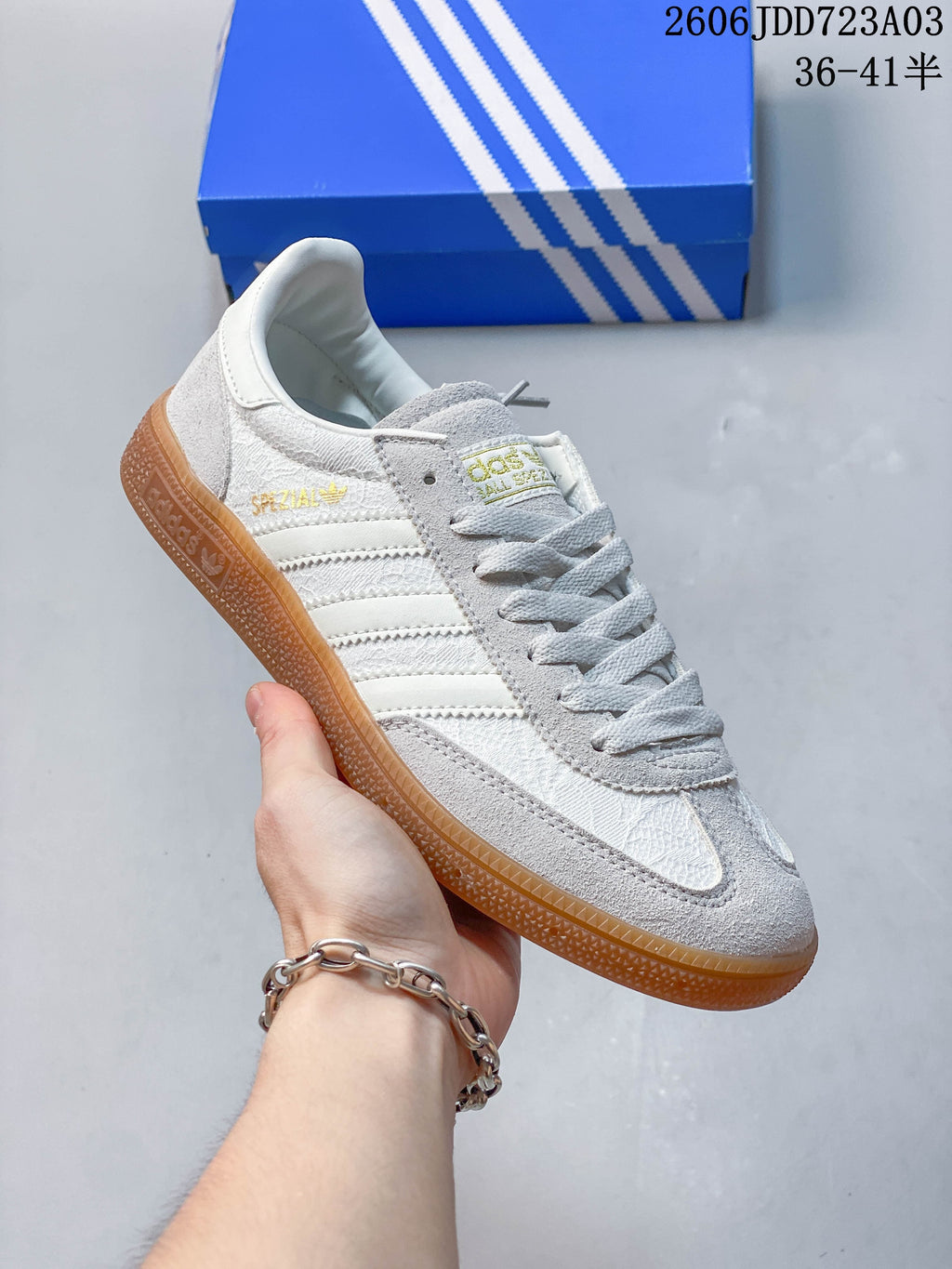Side view of a light gray Adidas Handball Spezial sneaker with pale stripes and a gum-colored outsole.
