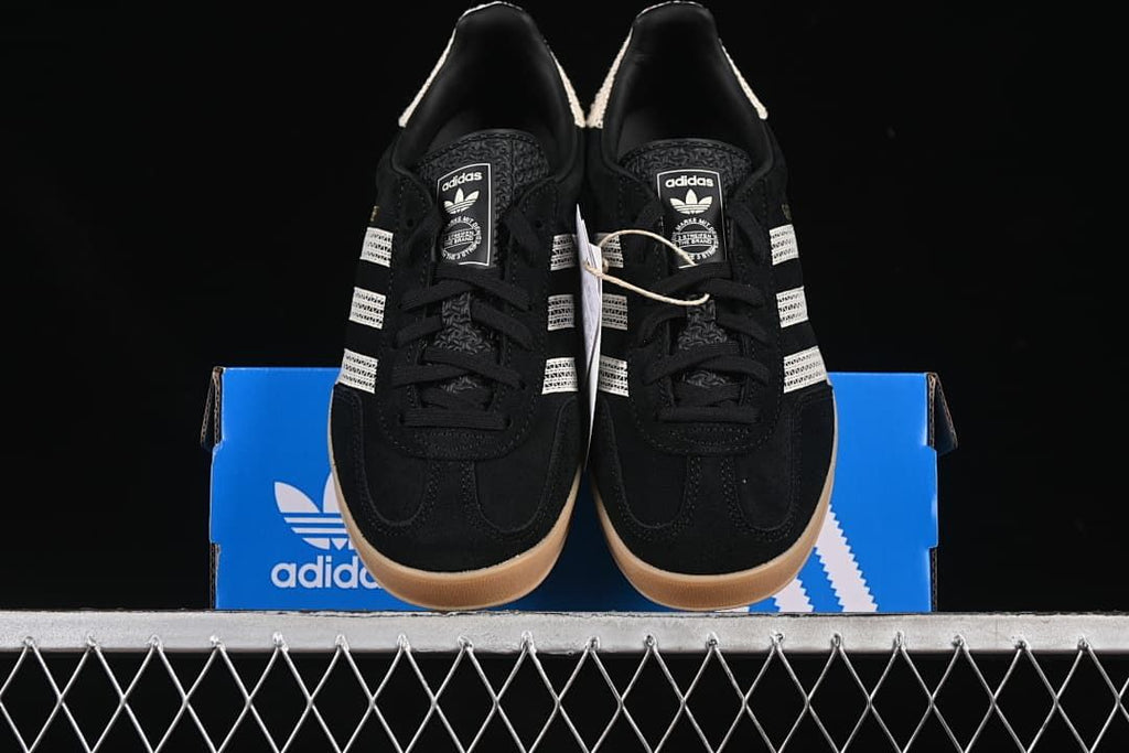 Front view of the pair of black low-top sneakers displayed on a blue box.