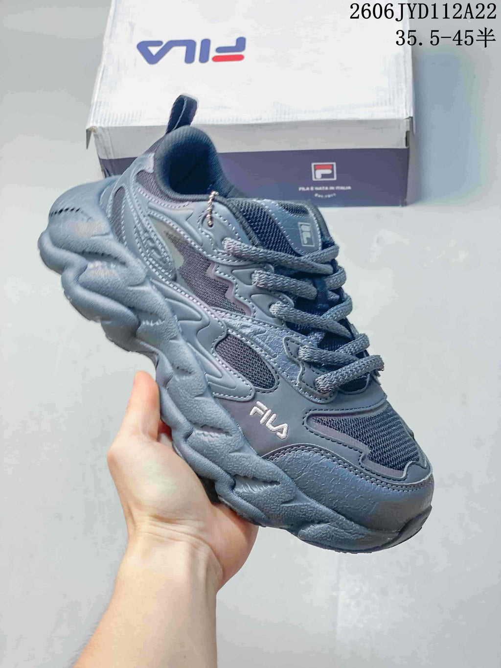Close view of a gray-blue FILA lace-up sneaker with mesh panels and a chunky sole.
