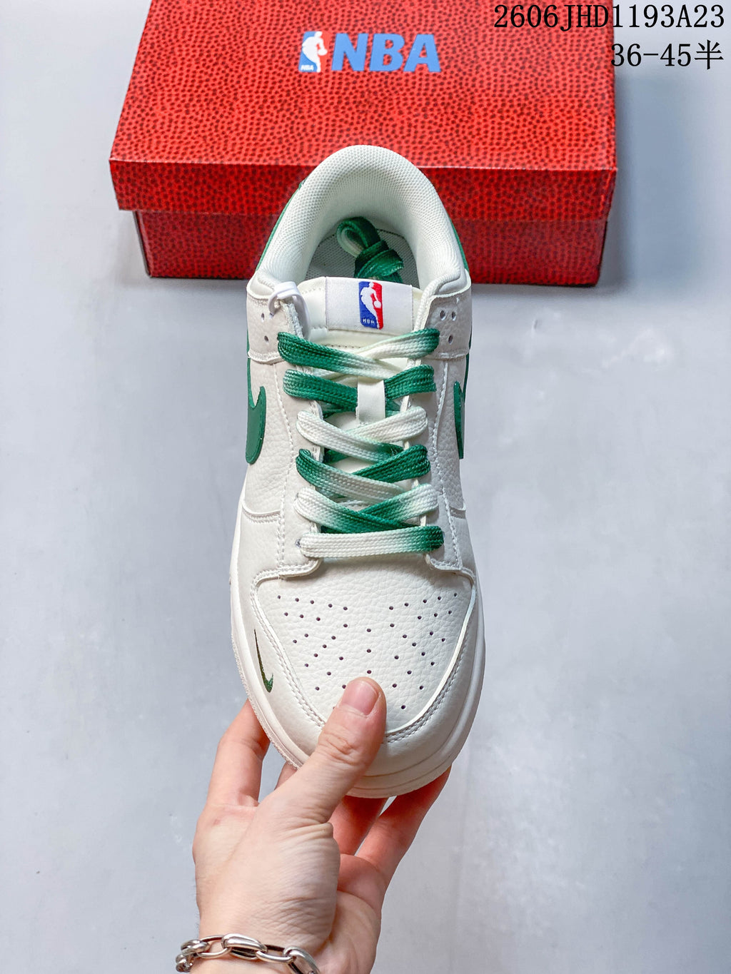 Top view of a white and green low-top sneaker with mixed-color laces and a perforated toe