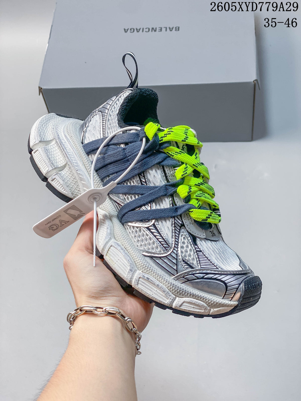 Close view of a silver and white Balenciaga Phantom sneaker with neon-yellow and dark blue laces.