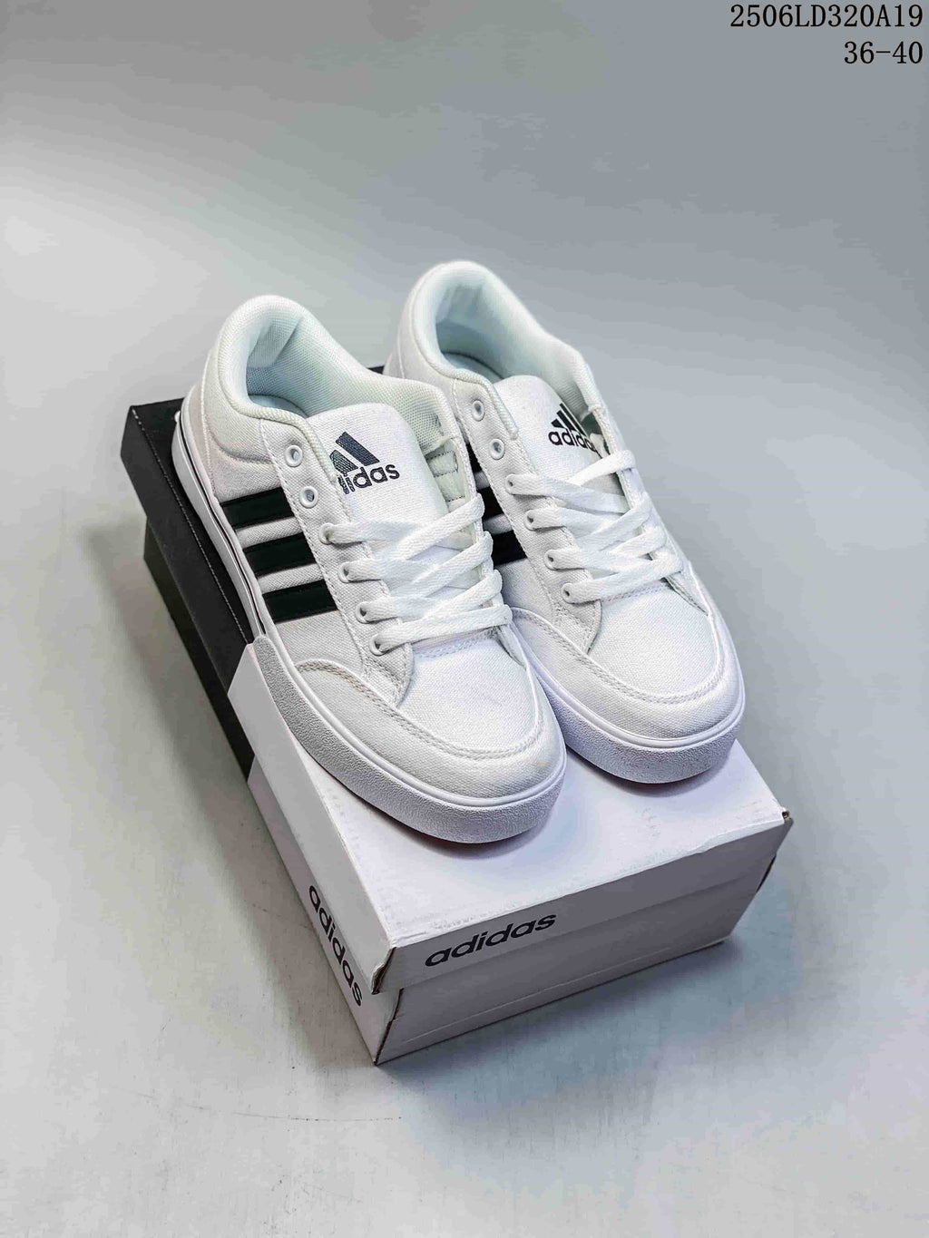 Pair of white Adidas low-top lace-up sneakers with black side stripes, shown on a shoebox.