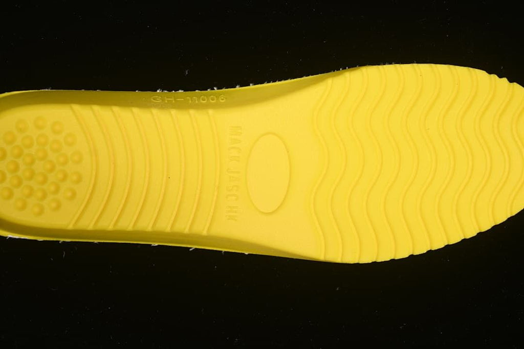 Close-up of the yellow outsole insert with molded tread and markings.