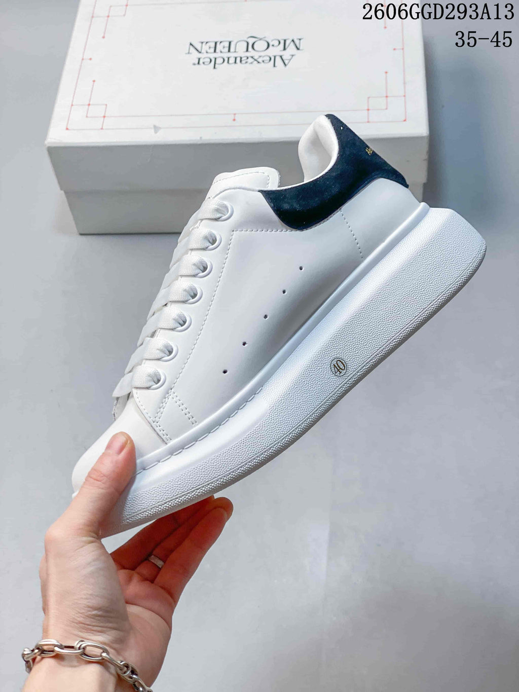 Side view of a white sneaker with perforated details, black heel tab, and thick sole
