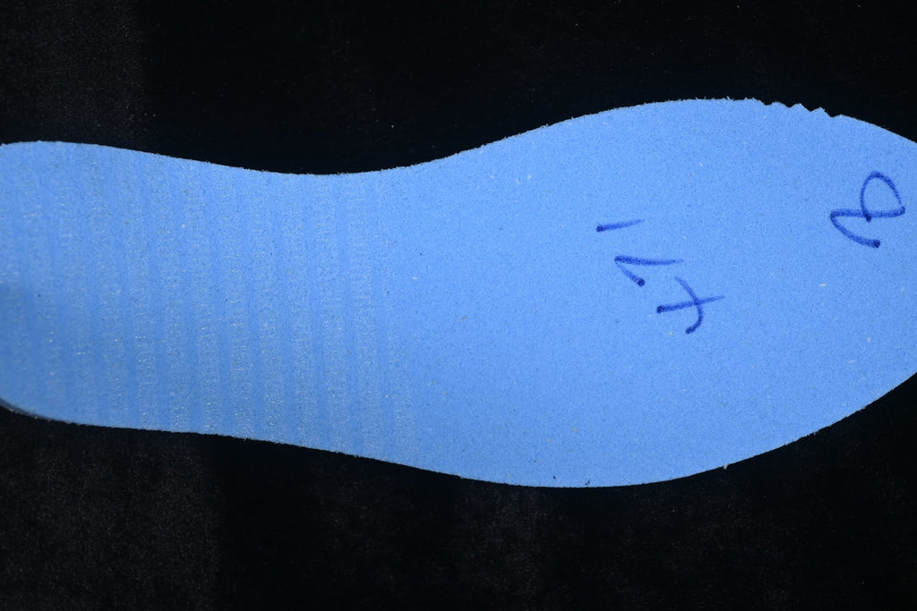 Reverse side of a shoe insole with handwritten markings.
